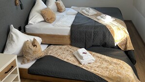 A double bed with a grey quilted bedspread and white pillows, a bedside table with a drawer, and a window with curtains. - Apartment in Jochberg With Ski-in/out (Jochberg)