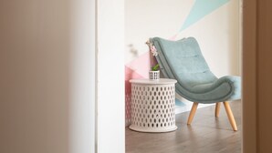 Moderni huone, jossa on harmaa, verhoiltu tuoli, valkoinen, rei’itetty sivupöytä ja pieni ruukkukasvi.