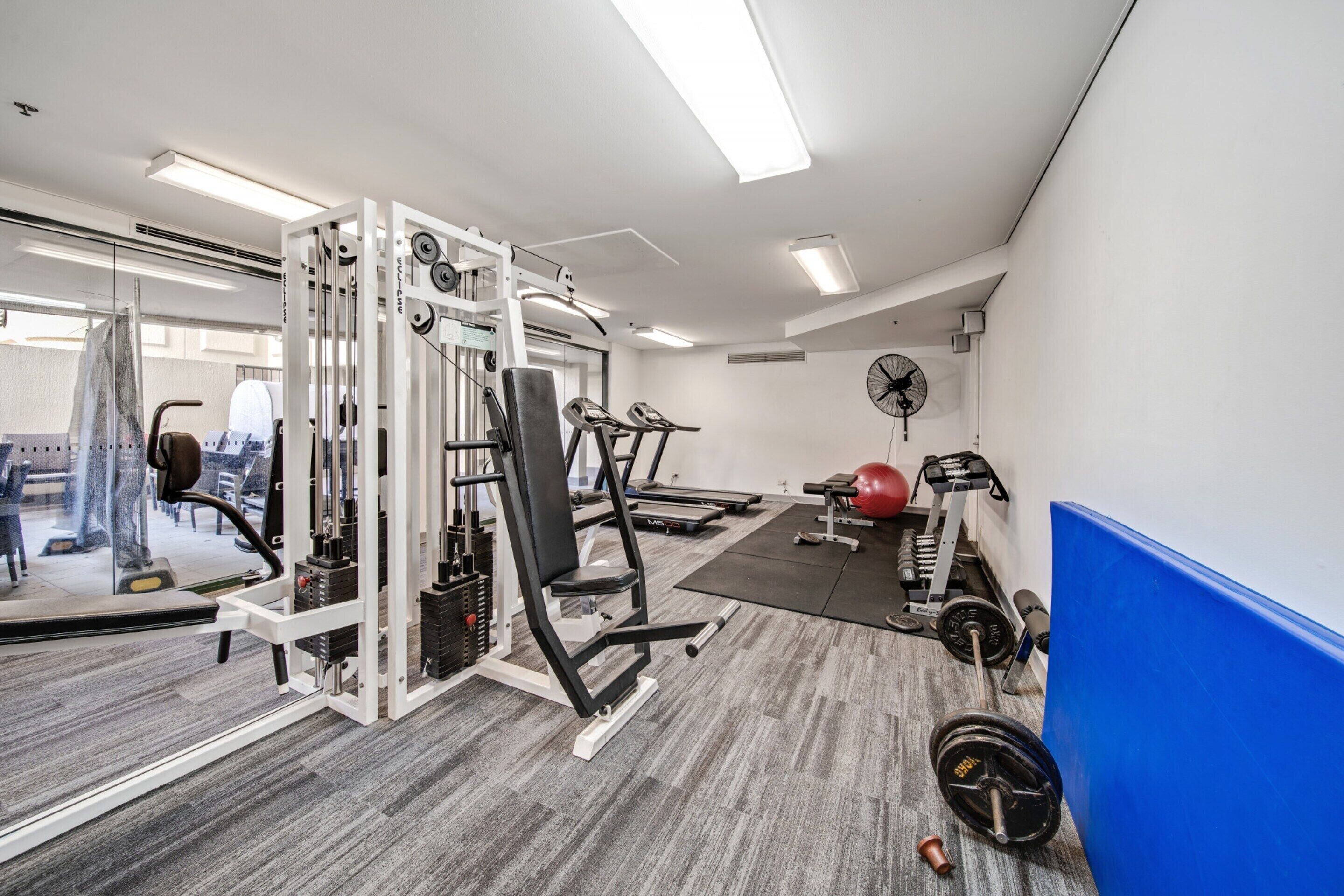 A gym with exercise equipment, a treadmill, and a weight bench.