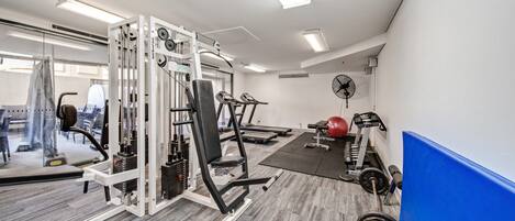 A gym with exercise equipment, a treadmill, and a weight bench.