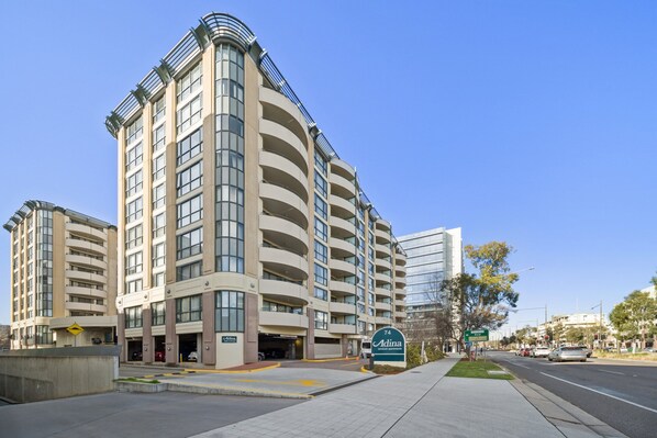 A multi-story hotel with a curved facade, a parking garage, and a clear sky. - Central 2-bed Apartment With Pool, Gym and Spa (Canberra)