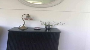 A bathroom vanity with a round mirror, a wall-mounted light fixture, and a vase with flowers. - 4 Star Holiday Home in Nykobing Sj (Nykobing Sjaelland)