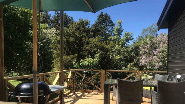 A wooden deck with outdoor furniture, a grill, and a bicycle. - 4 Star Holiday Home in Nykobing Sj (Nykobing Sjaelland)
