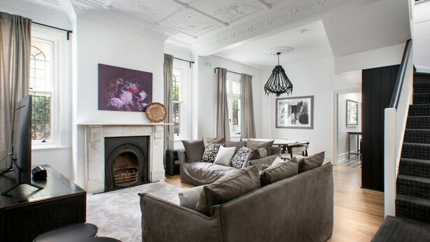 A spacious living room with a fireplace, a sofa set, and a staircase. - Elegant 3-bed Heritage House With Swimming Pool (Sydney)