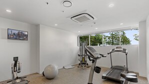 Un gimnasio moderno con máquinas de cardio, una máquina de remo y una pelota de ejercicios grande.