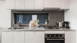 A modern kitchen with a stainless steel sink, a gas stove, and a built-in oven. - 2 bed Apartment in Trendy Collingwood (Melbourne)