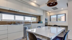 A modern kitchen with a central island, built-in appliances, and large windows. - Professional Living Minutes From the City (Sydney)