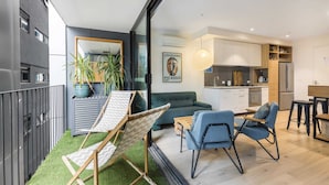A modern apartment with a living area featuring a sofa, two chairs, a small table, and a green wall with a Picasso poster. - City View Haven in South Melbourne (Melbourne)