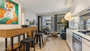 A modern kitchen with a wooden bar, black stools, and a large painting of a tiger. - City View Haven in South Melbourne (Melbourne)