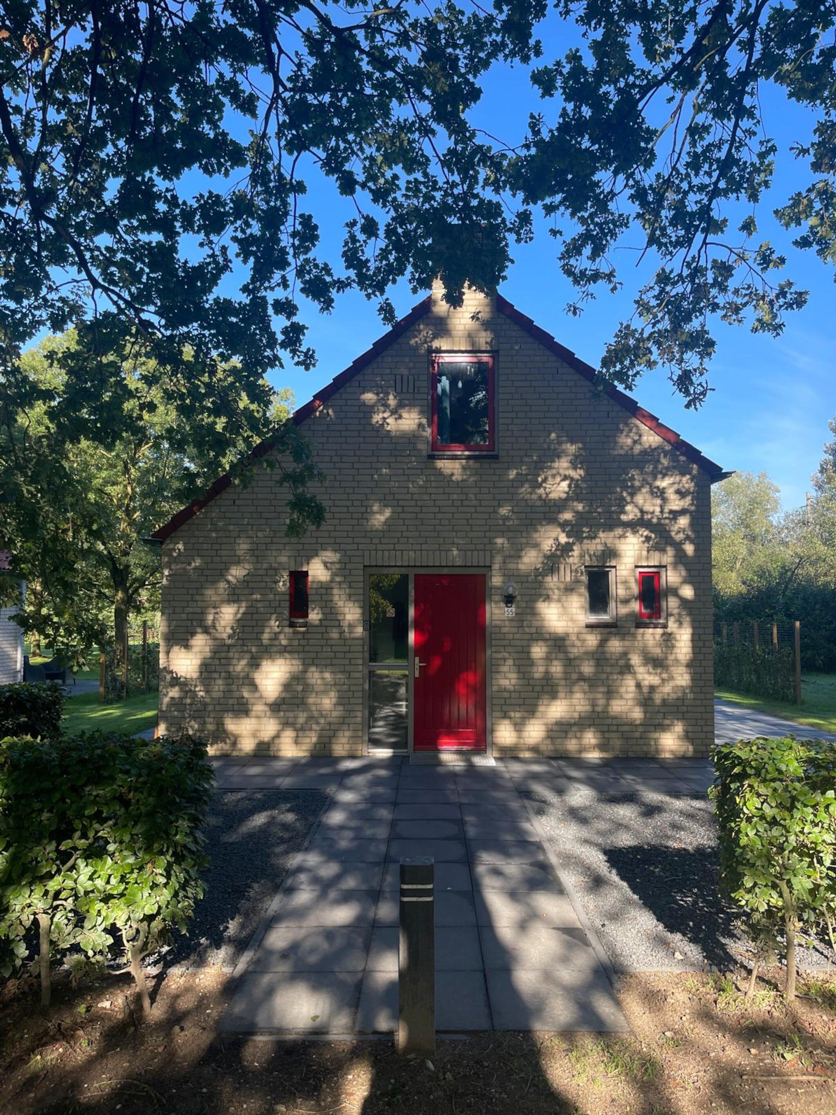 A small brick building with a red door, a small window, and a mailbox.