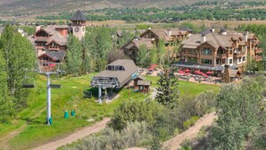 Un chalet comprenant plusieurs bâtiments, un télésiège et un espace de restauration avec des places assises en plein air.