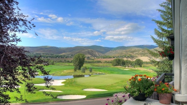 Blick vom Balkon auf einen Golfplatz mit Bergblick.