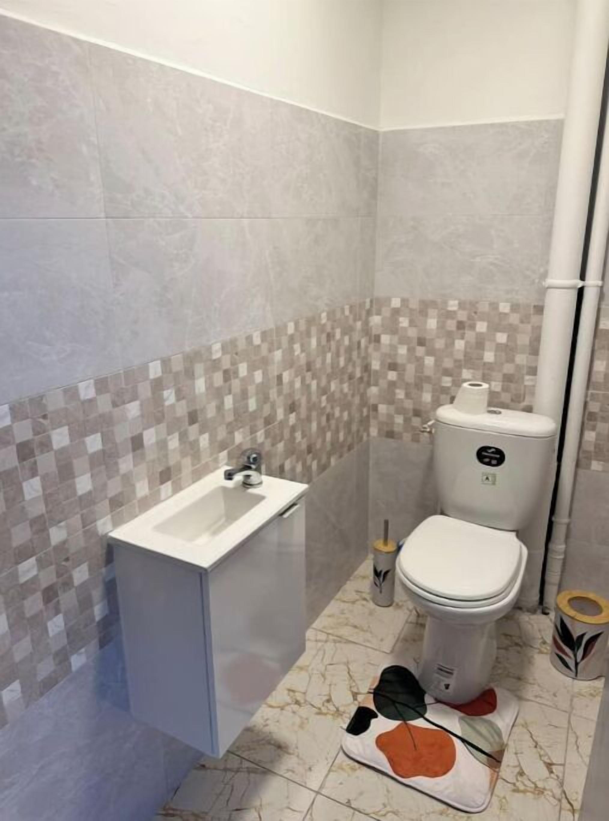 Een badkamer met een wit wastafel, toilet en betegelde vloer.