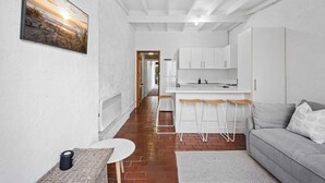 A modern kitchen with white cabinets, a bar area with stools, and a dining table.
