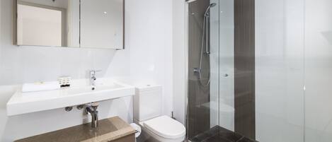 A modern bathroom with a white sink, a toilet, and a glass-enclosed shower.
