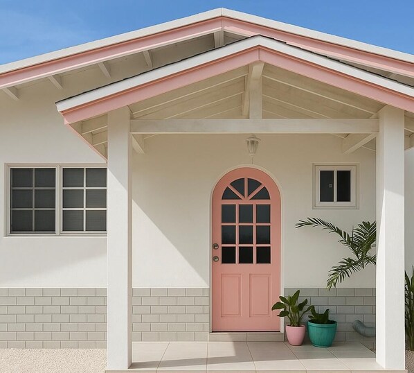 A house with a pink door, white walls, and a small porch area.