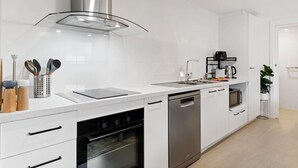 Een moderne keuken met witte kasten, roestvrijstalen apparatuur en een glazen kookplaat.