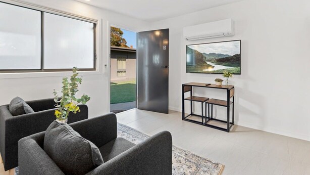 Een moderne woonkamer met een bank, een bijzettafeltje en een schilderij van een landschap.
