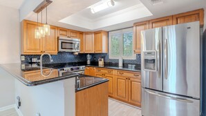 A modern kitchen with wooden cabinets, stainless steel appliances, and a black granite countertop.