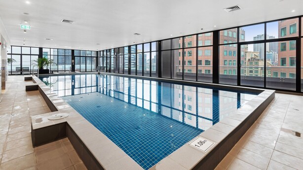 A modern indoor swimming pool with large windows and a city view.