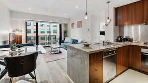 A modern kitchen with a central island, wooden cabinets, and stainless steel appliances.