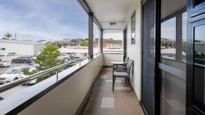 Ein Balkon mit Blick auf geparkte Autos und Gebäude.