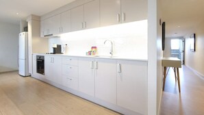 Eine moderne Küche mit weißen Schränken, einem eingebauten Backofen und einer Spüle aus Edelstahl.
