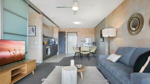 Un salon moderne avec un canapé gris, une table basse en bois et un téléviseur à écran plat.