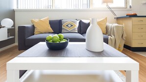 A modern living room with a sofa, a coffee table, and a bowl of green apples.