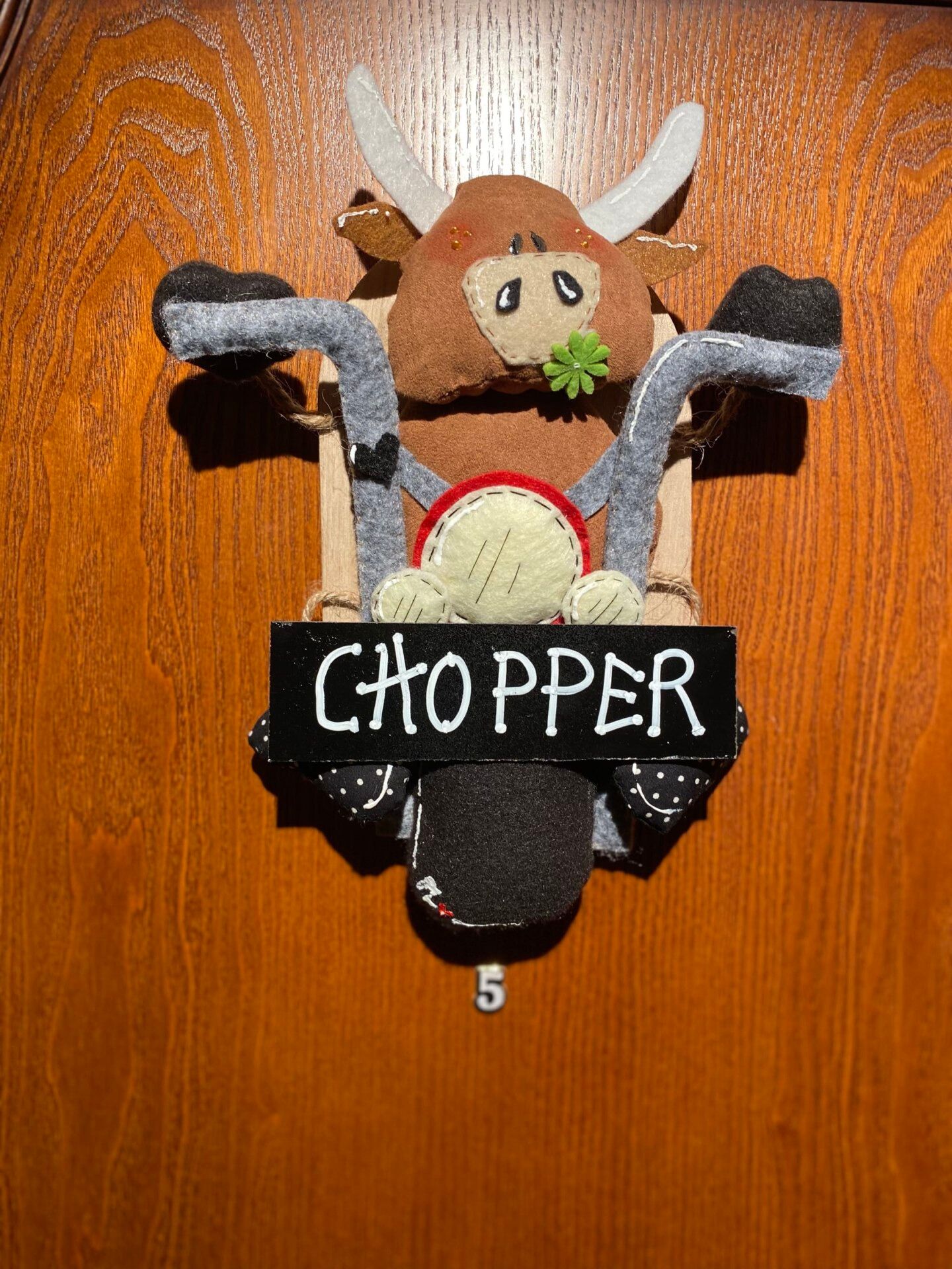 Una puerta de madera con un adorno de fieltro de un reno y un cartel que dice "CHOPPER".