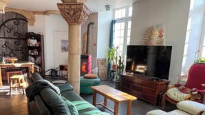 A spacious living room with a fireplace, leather sofas, a television, and a bookshelf. - Home Le Soft (Vic-sur-Cère)