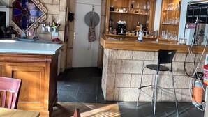 A kitchen with a stone island, wooden cabinets, and a bar area. - Home Le Soft (Vic-sur-Cère)
