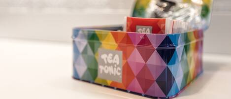 Una lata de té con un estampado geométrico colorido y la etiqueta "TEA TONIC" sobre una superficie blanca.