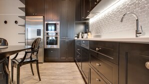 A modern kitchen with dark cabinetry, stainless steel appliances, and a white countertop. - Family Retreat In Top Blue Mountains Location (Katoomba)