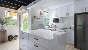 Eine moderne Küche mit weißen Schränken, einem Edelstahlkühlschrank und einer großen Kücheninsel mit Schubladen.