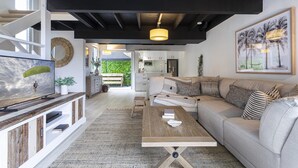 Ein modernes Wohnzimmer mit Sofa, Couchtisch, Fernseher und einer Treppe zu einer oberen Ebene.