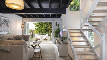 Un intérieur moderne avec un escalier, un canapé, une table à manger et une vue sur l’extérieur.