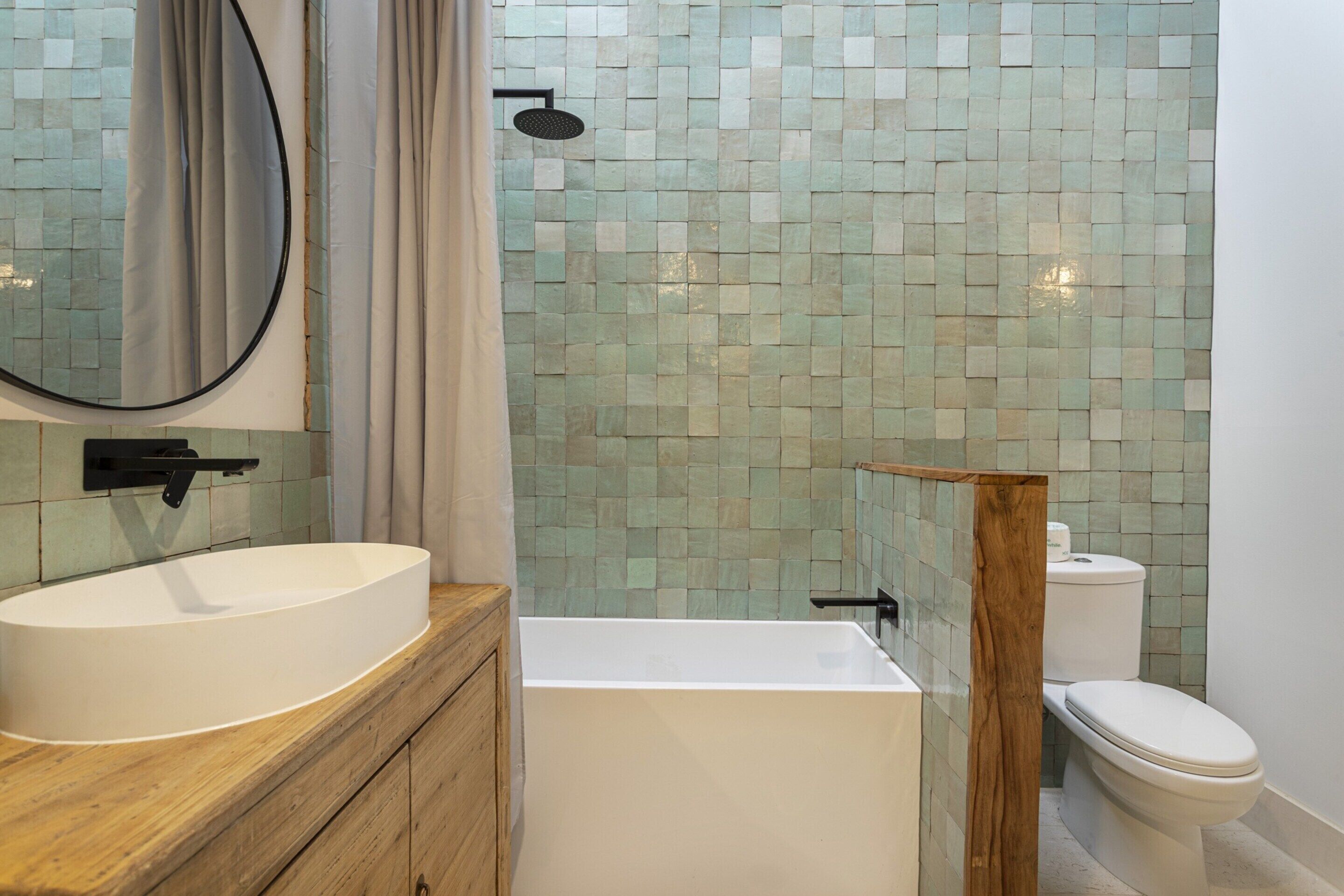 A bathroom with a white sink, wooden vanity, a bathtub, a toilet, and a shower with a glass enclosure.