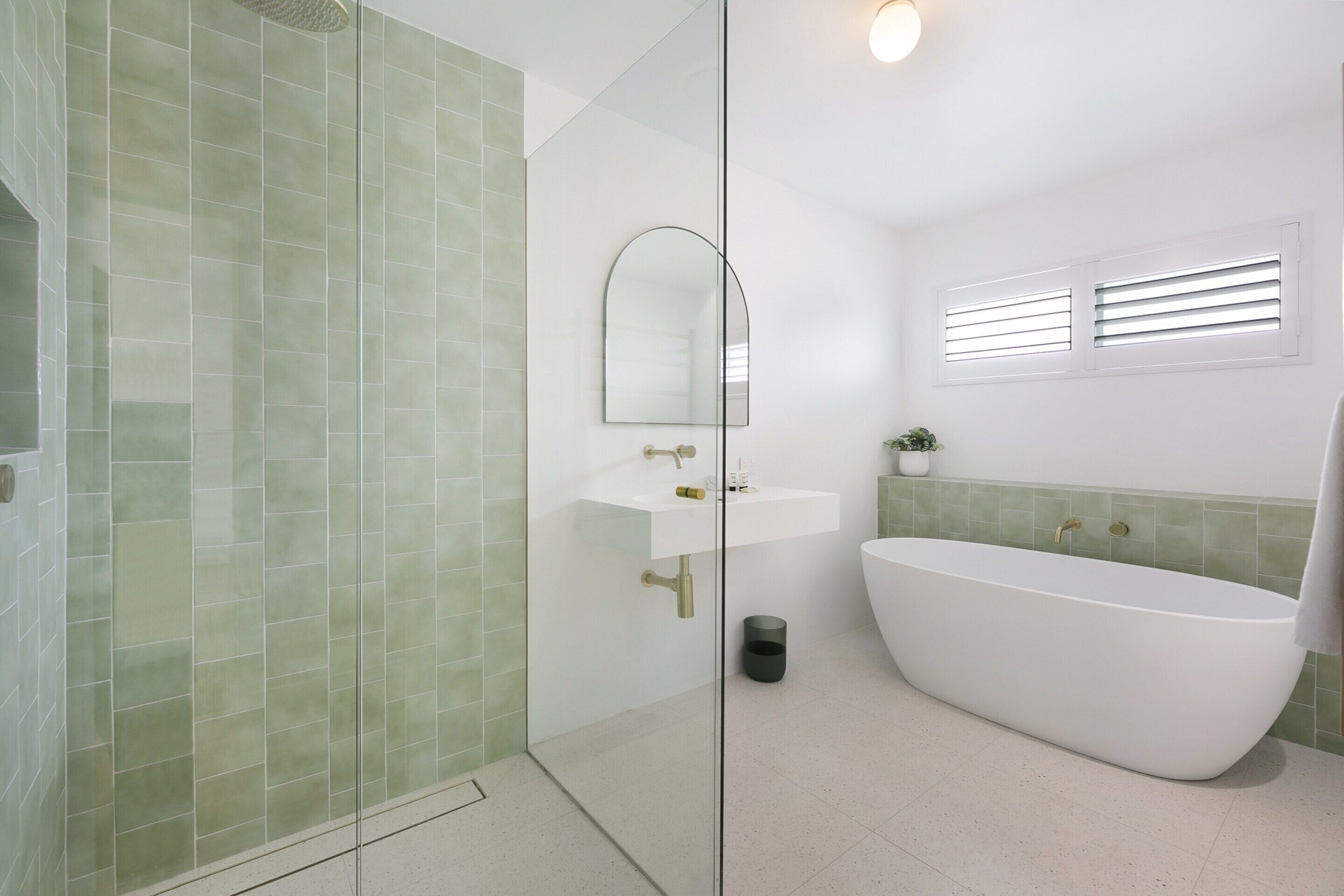A modern bathroom with a freestanding bathtub, a glass-enclosed shower, and a white sink with a mirror above it.