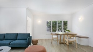 A modern living room with a teal sofa, a round wooden table, and a bench. - Spacious 4-bed Villa With Mediterranean Charm (Gold Coast)