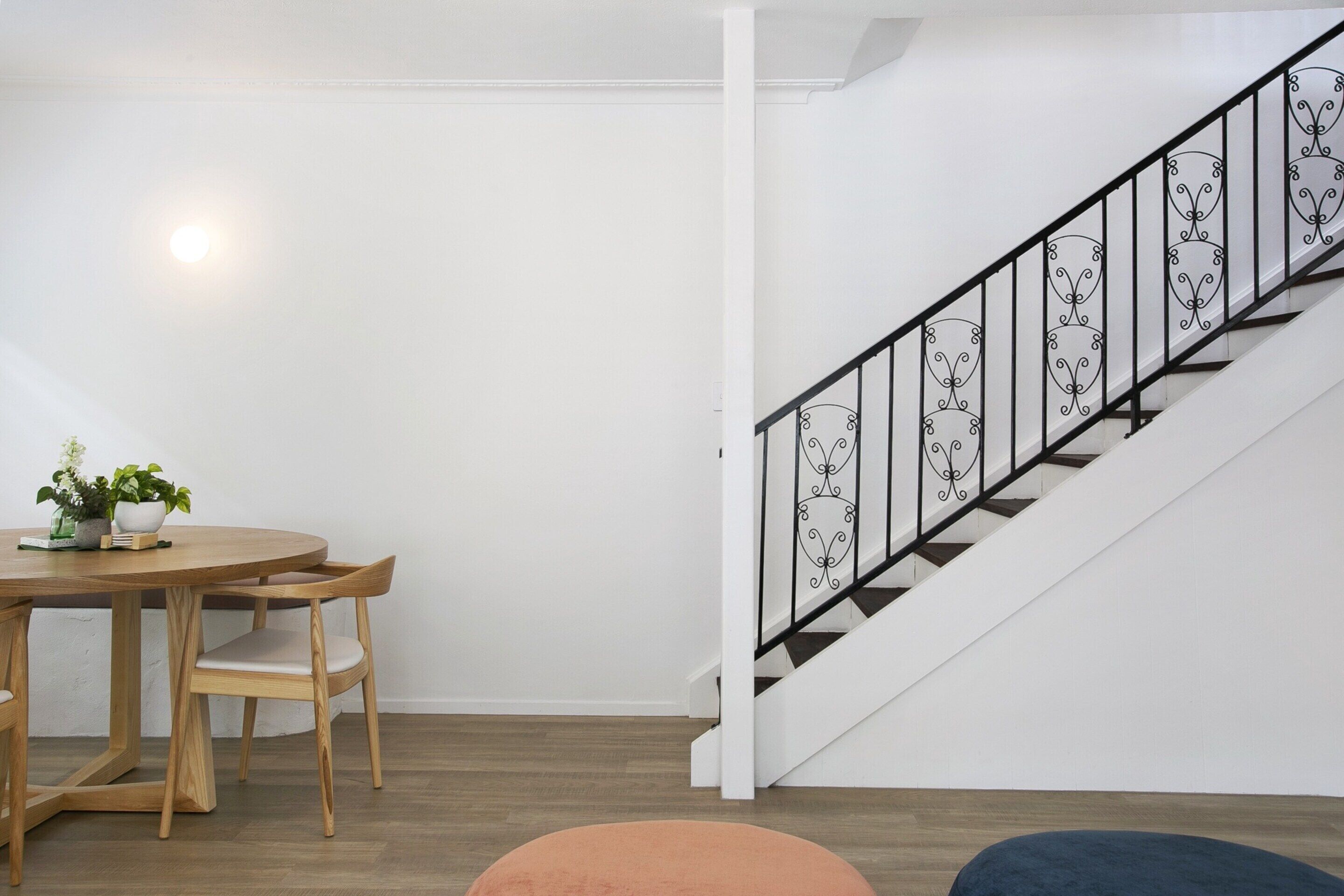 Una escalera con barandilla de metal negro y piso de madera.