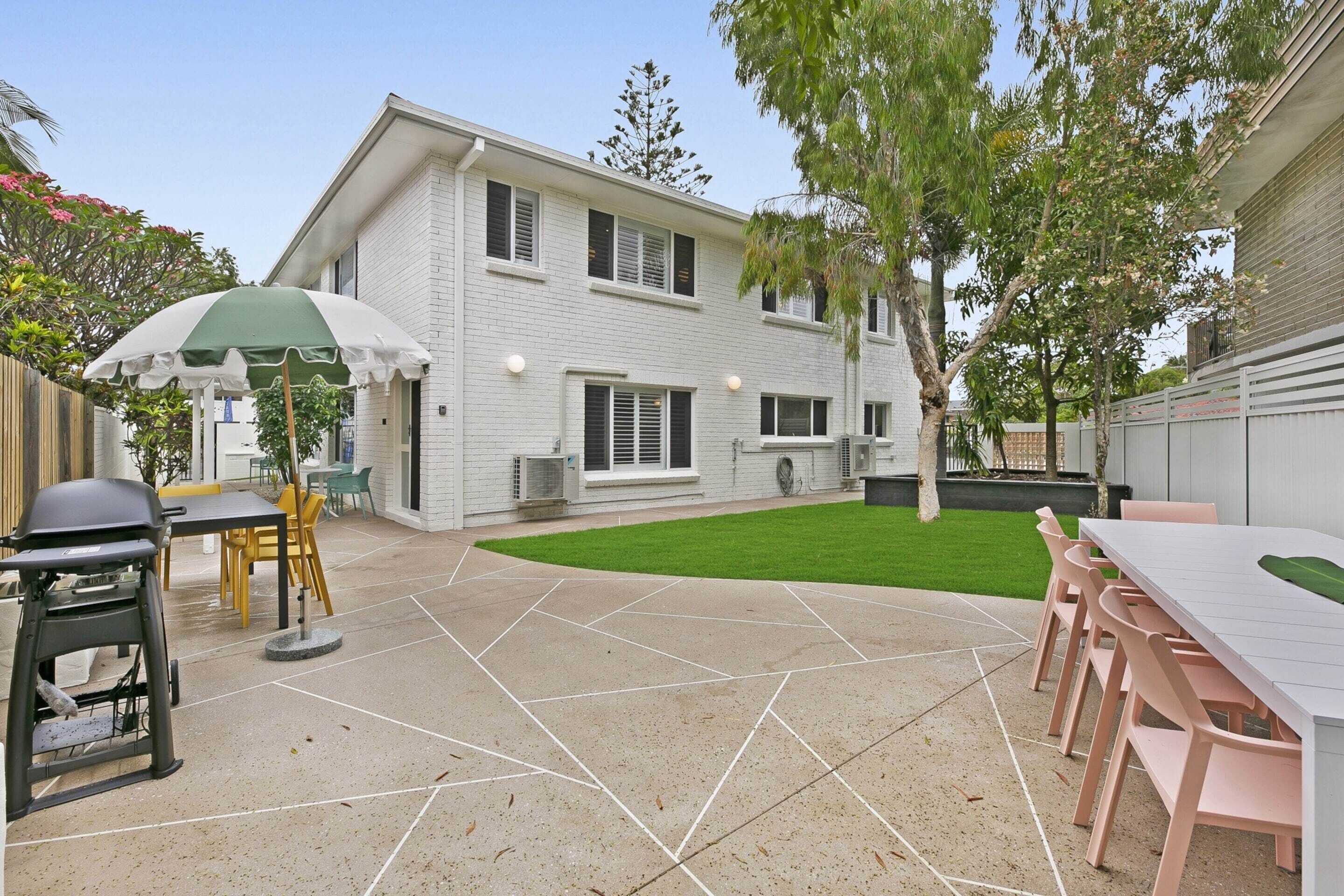 A patio with a table and chairs, a grill, and a lawn.