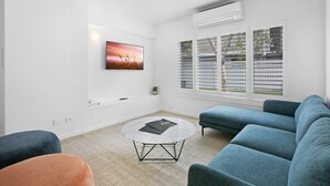 A modern living room with a round coffee table, a blue sofa, and a painting on the wall. - Spacious 4-bed Villa With Mediterranean Charm (Gold Coast)