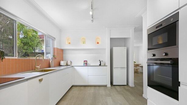A modern kitchen with white cabinetry, a stainless steel oven, and a window providing a view of the outdoors. - Spacious 4-bed Villa With Mediterranean Charm (Gold Coast)