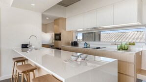 Een moderne keuken met een centraal eiland, barstoelen en uitzicht op de stad door een groot raam.