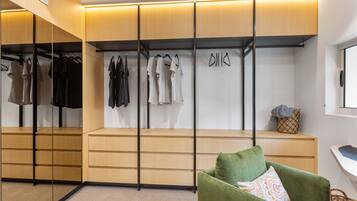 A modern walk-in closet with wooden shelving, a mirrored section, and a green armchair.