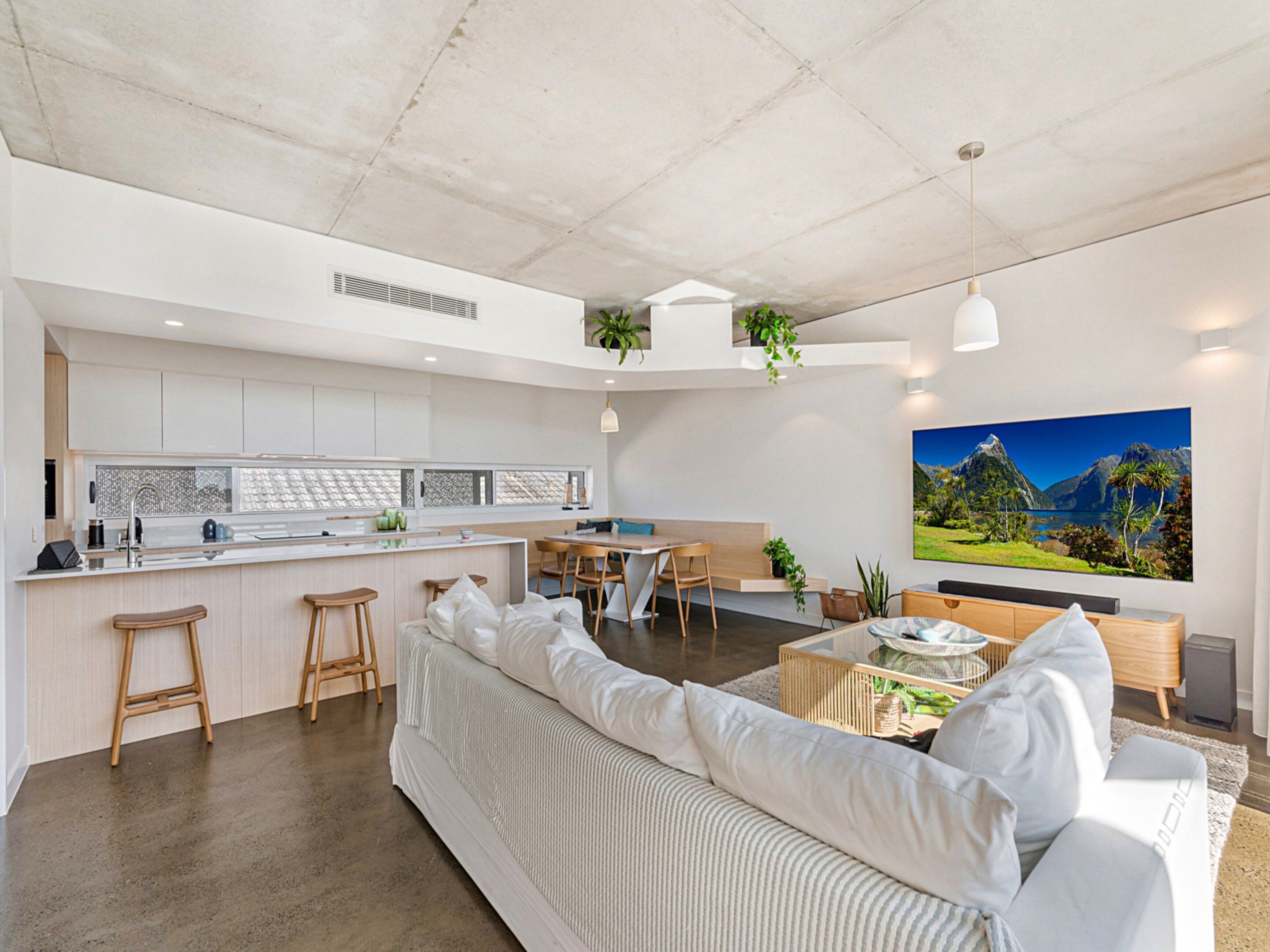 A modern kitchen with a central island, bar stools, and a dining area with a table and chairs.