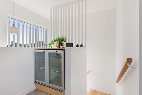A modern kitchen with a built-in refrigerator, a window with blinds, and a wooden shelf with a potted plant. - Luxury 5-floor Unit With Ocean Views Near Beach (Sunshine Coast)