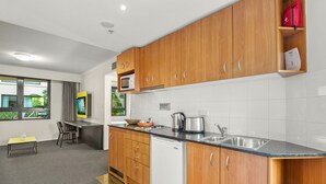 Una cocina moderna con armarios de madera, microondas, fregadero y cafetera.