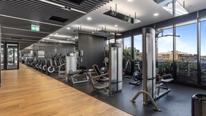 Una palestra moderna con attrezzature per esercizi, ampie finestre e pavimento in legno.